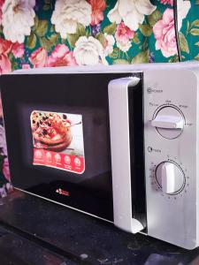un horno microondas con una foto de una pizza en Chambre Meublé avec Toillette intérieure chauffe eau Wi-Fi Smart Tv, en Dakar