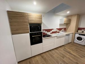 a kitchen with white cabinets and a washer and dryer at Gîte DouDou in Saint-Sever +25 photos