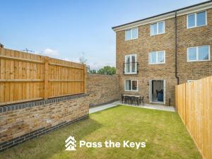 a garden with a wooden fence and a brick building at Pass the Keys Modern Townhouse with Garden and Parking in Ascot in Ascot