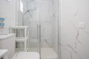 a white bathroom with a shower and a toilet at PentHouse Loft - Terrace & Natural Pool in Gáldar
