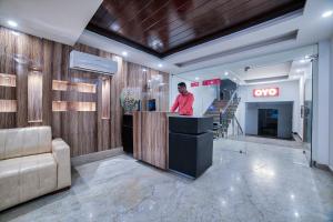 Un hombre de pie en un mostrador en un vestíbulo. en Hotel O Crown Residency, en Faridabad