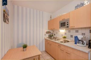 a kitchen with wooden cabinets and a counter top at Nur 100m zum Strand FeWo Seebrise 109 by Pro Home Appartements in Zempin