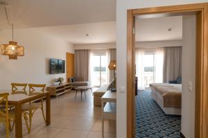 a hotel room with a bed and a dining room at Pestana Alvor Beach Villas Seaside Resort in Alvor +64 photos