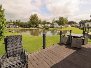 a deck with a table and chairs and a pond at 22 Yealand in Carnforth