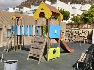 Un parque infantil con un tobogán y una estructura de juego. en Apartamento de 2 habitaciones con jardín y piscina comunitaria cerca de la playa en Pulpi - ES-376-24, en Pulpí