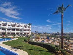 Una vista de un resort con piscina y palmeras. en Apartamento moderno en San Juan de los Terreros, cerca de la playa y piscina - ES-376-1, en Pulpí
