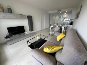 un soggiorno con divano grigio e cuscini gialli di Apartamento acogedor con piscina común en San Juan de los Terreros, cerca de la playa - ES-376-13 a Pulpí