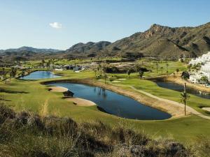 einen Golfplatz mit Teich und Bergen im Hintergrund in der Unterkunft Casa acogedora cerca de la playa en San Juan de los Terreros - ES-376-9 in Pulpí