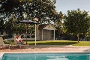 奎特里拉Outsite Vilamoura的坐在游泳池旁伞下的女人