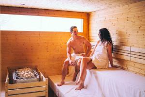 a man and woman sitting on beds in a sauna at Apartment in Zalakaros - Thermalbad 20682 in Zalakaros