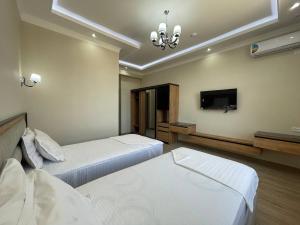 a bedroom with two beds and a flat screen tv at Saroy Khiva in Khiva
