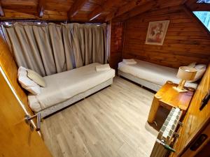 a room with two beds in a log cabin at El Remanso - Arrayan Cabin, Bahía Manzano in Villa La Angostura