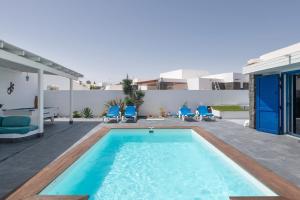 a swimming pool with blue chairs and a house at Villa Lunamoon, Playa Blanca in Playa Blanca
