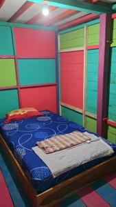 Pulau SarangにあるSurf House Hostelのカラフルなドア付きのベッドルーム1室、ベッド1台が備わる客室です。