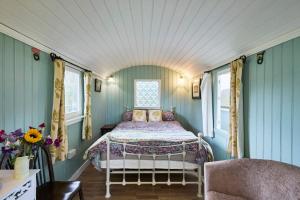 a bedroom with a bed in a room with blue walls at Host & Stay - Shepherd's Hut in Briston +9 photos