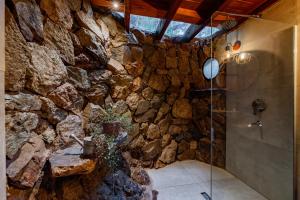 a stone bathroom with a shower and a stone wall at Complejo de Cabañas Ideales para parejas in San Carlos de Bariloche