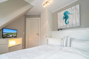 a bedroom with a white bed and a television at Strandpirat in Wenningstedt