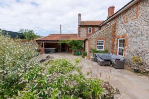 an external view of a brick house with a patio at Studio Sleeps 2 w HotTub-Garden-PetsOK-Parking in Cromer