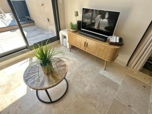 a living room with a flat screen tv and a table at Appartement à Collioure pour familles avec piscine et parking - FR-1-309-529 in Collioure