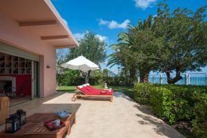 メソギーにあるCorfu Beachfront Villaの赤いソファとパラソル付きのパティオ