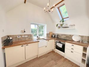 a kitchen with white cabinets and a window at The Dairy cottage with garden and parking in Olveston