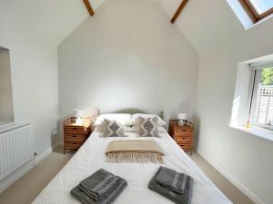 a white bedroom with a large bed with two night stands at The Dairy cottage with garden and parking in Olveston +7 photos