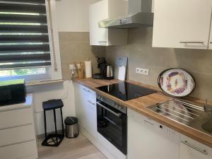 a kitchen with white cabinets and a black stove top oven at Holunder nah am Waldsee 3 in Rieden