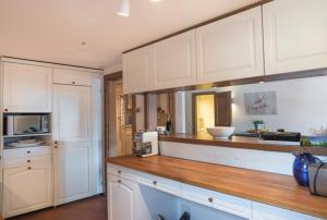 a kitchen with white cabinets and a wooden counter top at Edelweiss Ferienwohnung, Casa Dadens, Flims Dorf , 6027 in Flims