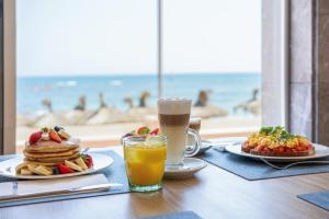 Una mesa con dos platos de panqueques y un vaso de jugo de naranja. en Hotel THB Gran Bahía, en Can Picafort 75 fotos más