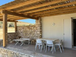 a patio with a table and chairs and a stone wall at Sohoro Villas in Koufonisia