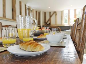a table with a plate of croissants and glasses of orange juice at Tatters Barn in Bradwell +12 photos