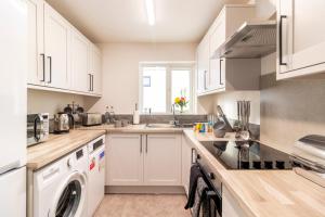 a kitchen with white cabinets and a washer and dryer at WOW! SeaView Beach Apartment Sleeps 6-Free Parking in Bournemouth