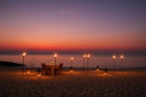 a dinner table on the beach at sunset at Amāra Beach Eco Hotel in Dibulla