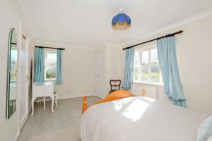 a bedroom with a bed and blue curtains and a desk at Finest Retreats - Corrennie School Cottage in Inverurie