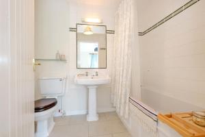 a bathroom with a sink and a toilet and a mirror at Finest Retreats - Corrennie School Cottage in Inverurie +13 photos