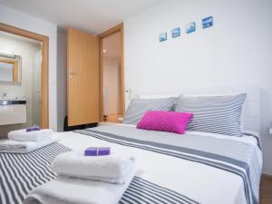a bedroom with a large white bed with a pink pillow at Apartment Heart of Trogir in Trogir