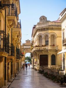 an alley with buildings and people walking down a street at Casa Sikelia in Marsala