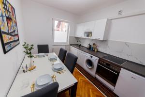 Una cocina con mesa y sillas y un microondas. en Khalilah Apartment 1, en Bihać