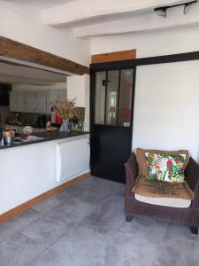 a living room with a chair and a kitchen at Chambres d'hôtes les hirondelles in Méa +4 photos