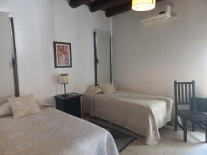 a bedroom with two beds and a table and a chair at Viamonte Rest in Ciudad Lujan de Cuyo