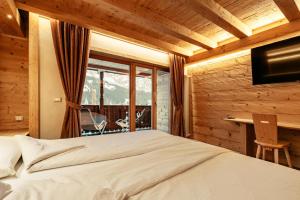 a bedroom with a bed and a desk and a window at Alpenlieben B&B in Sappada