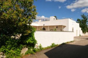 a white house behind a white wall at Masseria Kalandini in Corigliano dʼOtranto