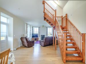a wooden staircase in a living room with chairs at Meadowgreen Farmhouse in Forfar