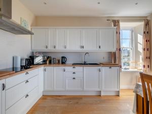 a kitchen with white cabinets and a sink at Meadowgreen Farmhouse in Forfar +16 photos