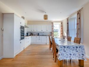 a kitchen with white cabinets and a table with chairs at Meadowgreen Farmhouse in Forfar