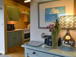 eine Küche mit grünen Schränken und einer Vase mit Blumen auf dem Tisch in der Unterkunft Timbers in Woolfardisworthy