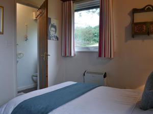 ein Schlafzimmer mit einem Bett und einem Fenster in der Unterkunft Timbers in Woolfardisworthy + 8 Fotos