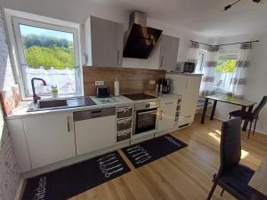 a kitchen with white cabinets and a sink and a window at Ferienwohnung zum Finkenbachtal in Oberzent