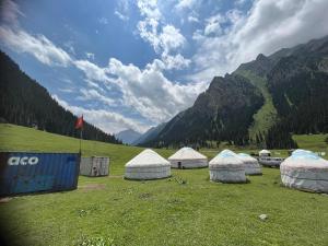 a group of four tents in a field with mountains at Emin Sky Camp in Mineralʼnyy Istochnik Altyn-Arasan