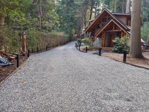 a gravel driveway in front of a log cabin at El Remanso - Arrayan Cabin, Bahía Manzano in Villa La Angostura